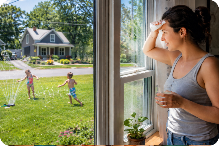 Image of a mom watching her kids play with the sprinkler through her window
